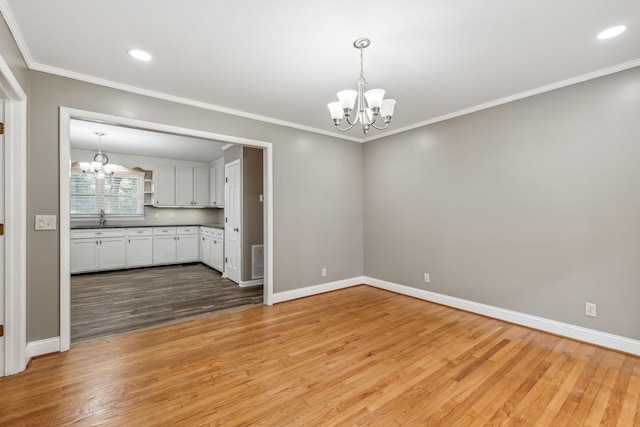 unfurnished dining area featuring an inviting chandelier, light wood-style floors, visible vents, baseboards, and ornamental molding
