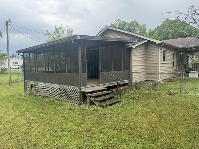 rear view of property with fence, a yard, and a sunroom