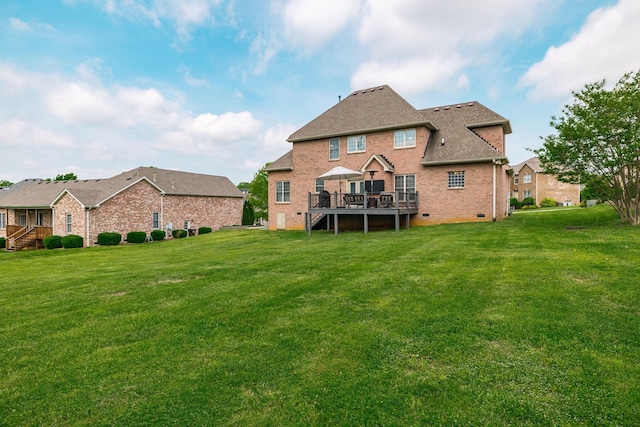 rear view of house featuring roof with shingles, brick siding, a wooden deck, crawl space, and a yard