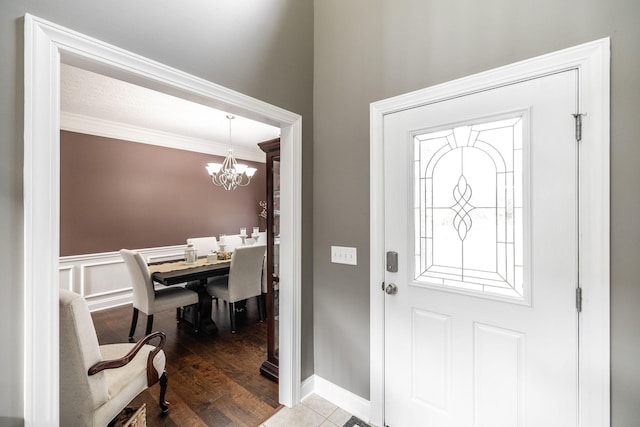 foyer entrance featuring baseboards, ornamental molding, and a chandelier