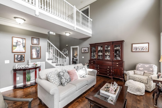 living area featuring wood finished floors, stairway, baseboards, ornamental molding, and a high ceiling