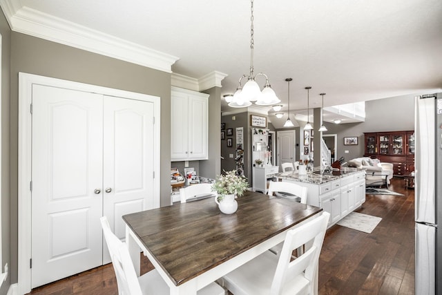 dining room with dark wood-type flooring, ornamental molding, and a chandelier