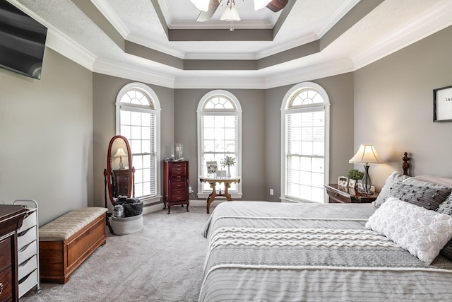 bedroom with a raised ceiling, ornamental molding, multiple windows, and light colored carpet