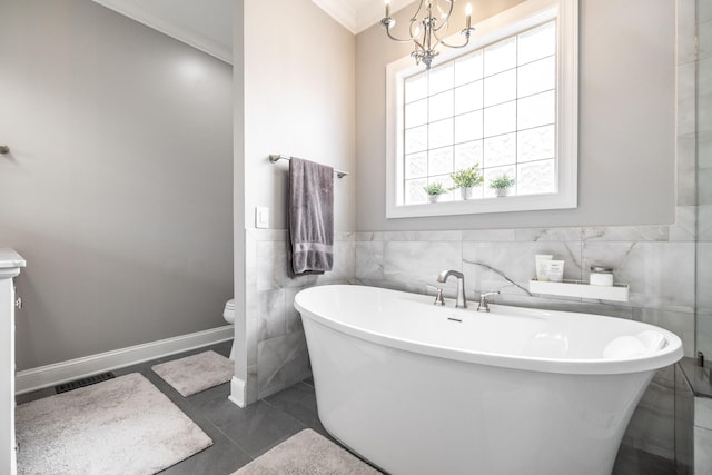 bathroom featuring visible vents, a freestanding tub, toilet, tile walls, and a notable chandelier
