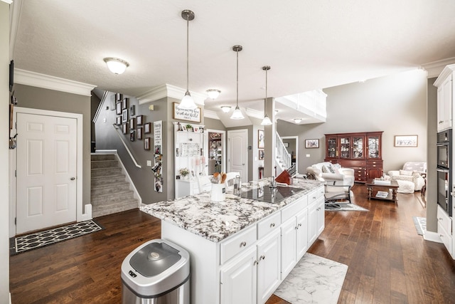 kitchen featuring ornamental molding, open floor plan, black electric stovetop, dark wood-style floors, and white cabinetry