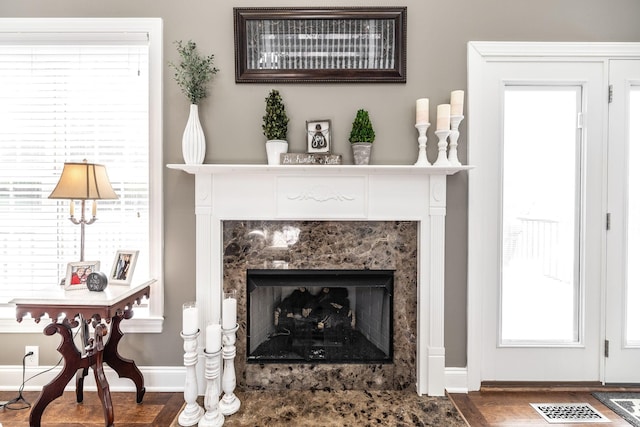 living area featuring baseboards, visible vents, wood finished floors, and a premium fireplace