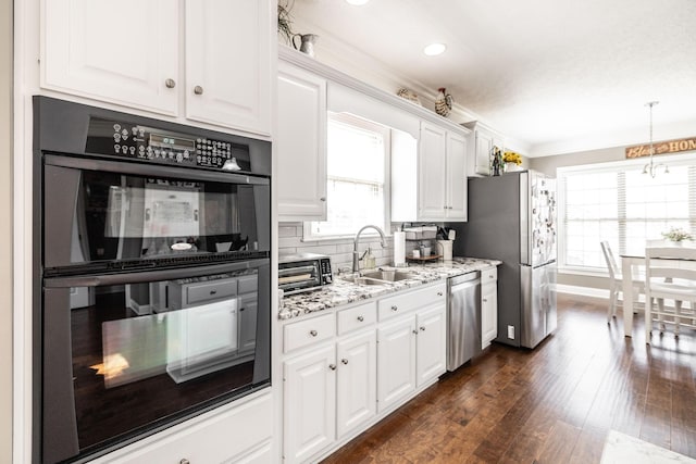 kitchen featuring light stone countertops, dark wood-type flooring, white cabinetry, a sink, and appliances with stainless steel finishes
