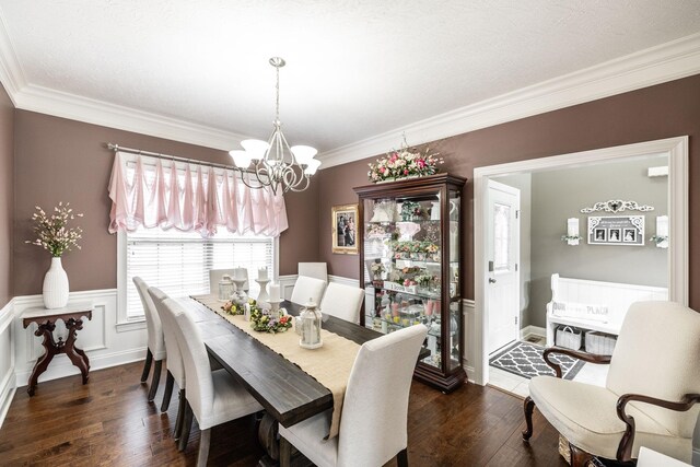 dining room with ornamental molding, wainscoting, dark wood-style floors, and a notable chandelier