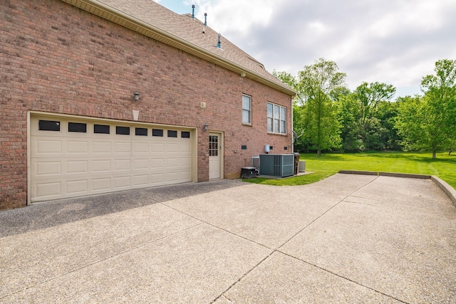 view of side of home with central AC unit, a yard, driveway, and brick siding