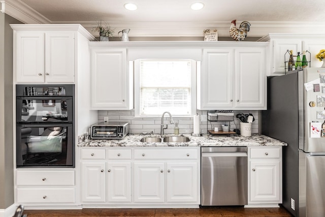 kitchen with white cabinets, light stone counters, a sink, stainless steel appliances, and a toaster
