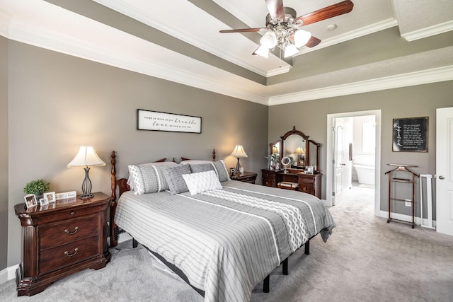 bedroom featuring ornamental molding, ensuite bathroom, baseboards, light colored carpet, and a raised ceiling