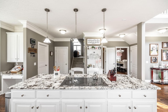 kitchen featuring crown molding, dark wood-style flooring, light stone countertops, black electric stovetop, and a center island