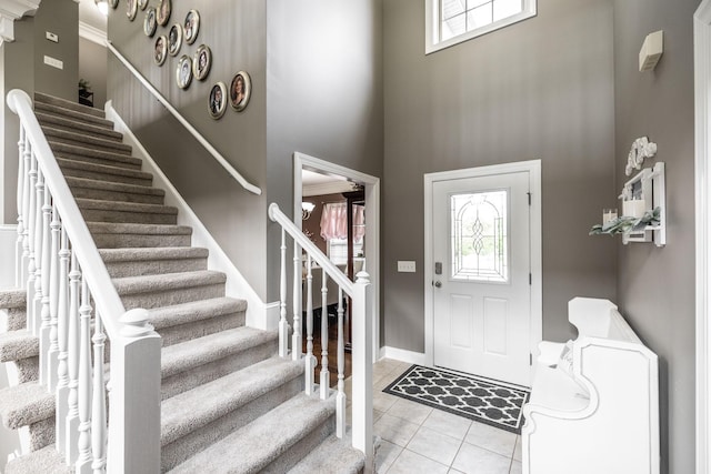 entryway featuring stairs, plenty of natural light, and a towering ceiling