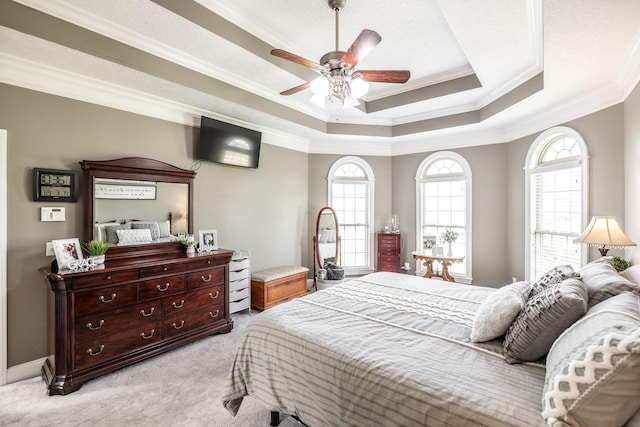 bedroom featuring crown molding, ceiling fan, a tray ceiling, and light carpet