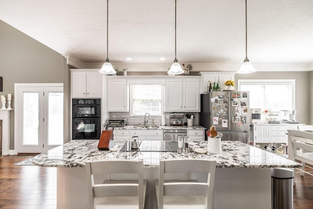 kitchen with a sink, ornamental molding, black appliances, and white cabinets