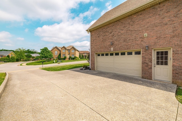 view of home's exterior with driveway, a residential view, brick siding, an attached garage, and a shingled roof