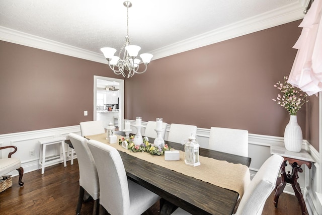 dining space featuring dark wood-style flooring, an inviting chandelier, ornamental molding, and a wainscoted wall