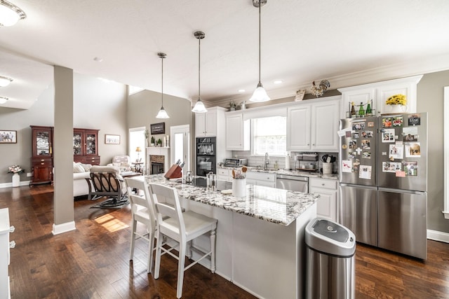 kitchen featuring a kitchen breakfast bar, tasteful backsplash, a sink, stainless steel appliances, and white cabinetry