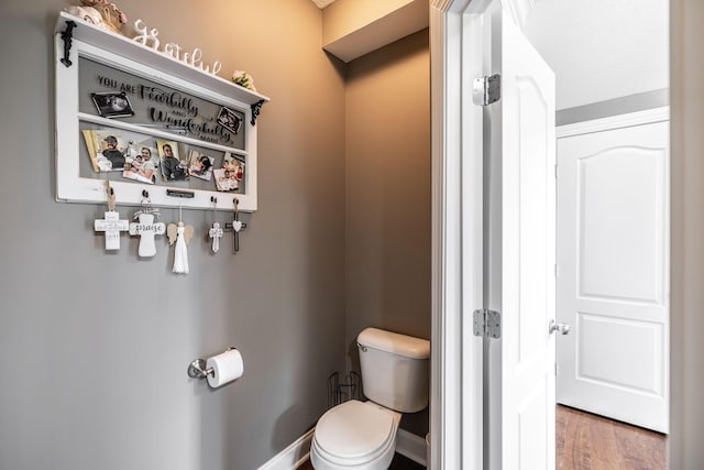 bathroom with baseboards, toilet, and wood finished floors