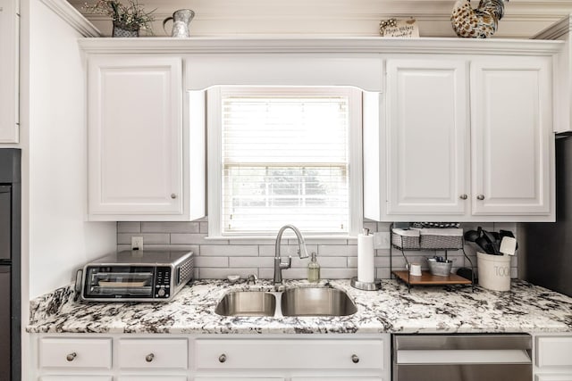 kitchen featuring tasteful backsplash, stainless steel dishwasher, a sink, a toaster, and white cabinetry