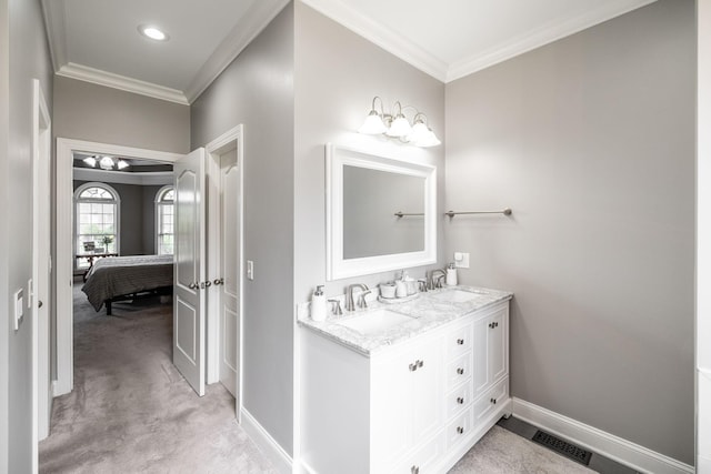 ensuite bathroom with visible vents, ornamental molding, and a sink