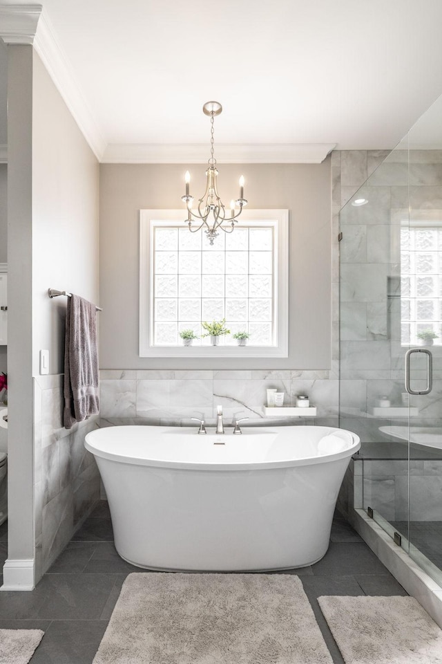 full bath with crown molding, an inviting chandelier, a freestanding tub, tile walls, and a shower stall