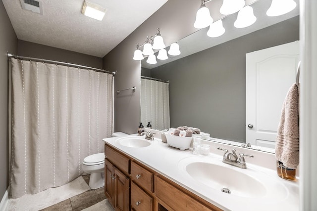 bathroom featuring visible vents, a sink, double vanity, and toilet