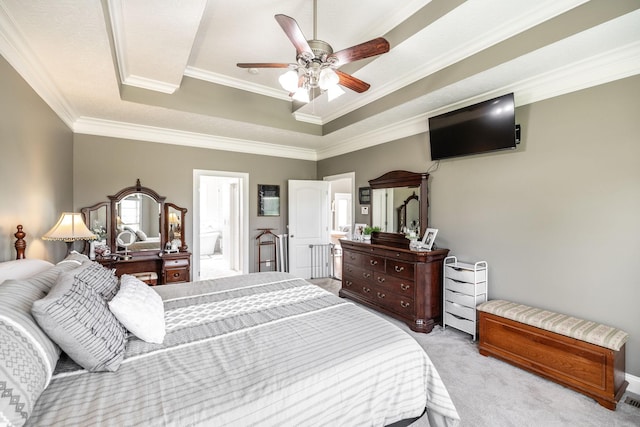 bedroom featuring ceiling fan, light carpet, ensuite bath, a tray ceiling, and ornamental molding