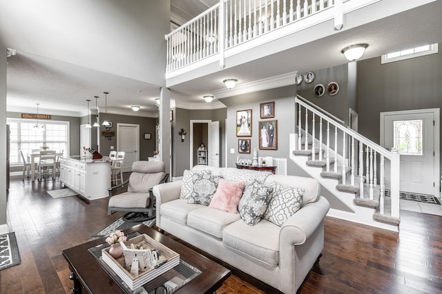 living area featuring crown molding, stairs, a towering ceiling, and dark wood-style flooring
