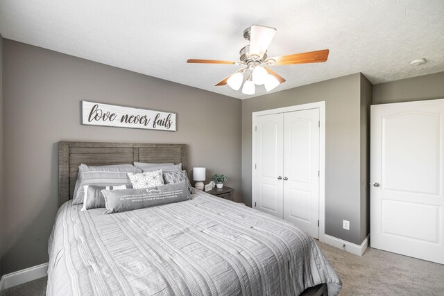 bedroom with baseboards, ceiling fan, a closet, and light colored carpet