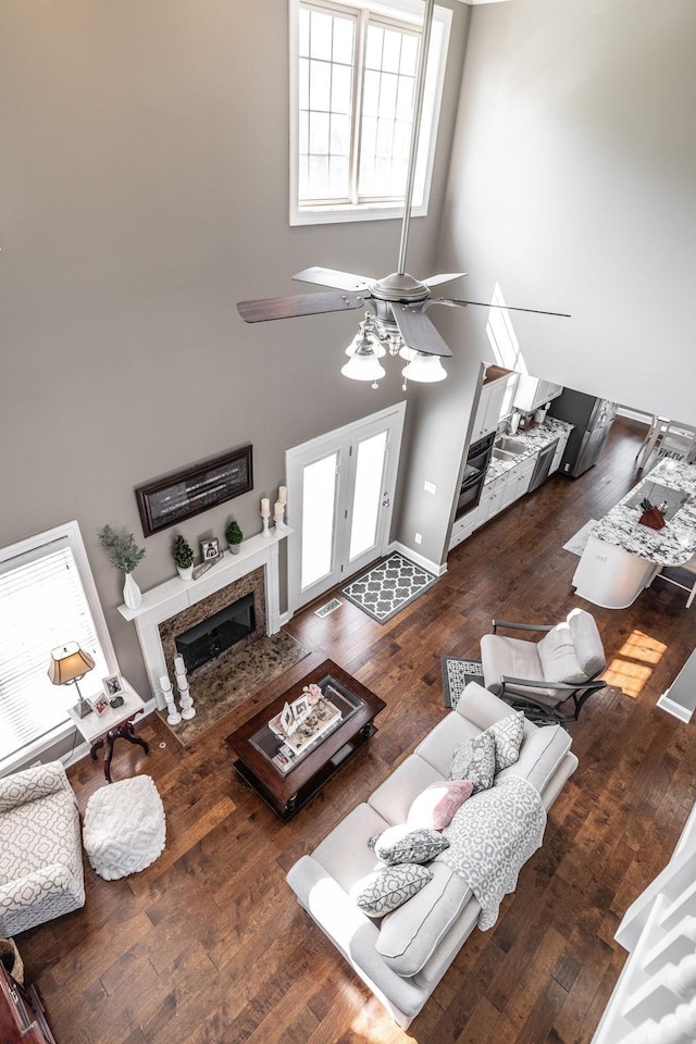 living area with wood finished floors, a high ceiling, ceiling fan, and a premium fireplace