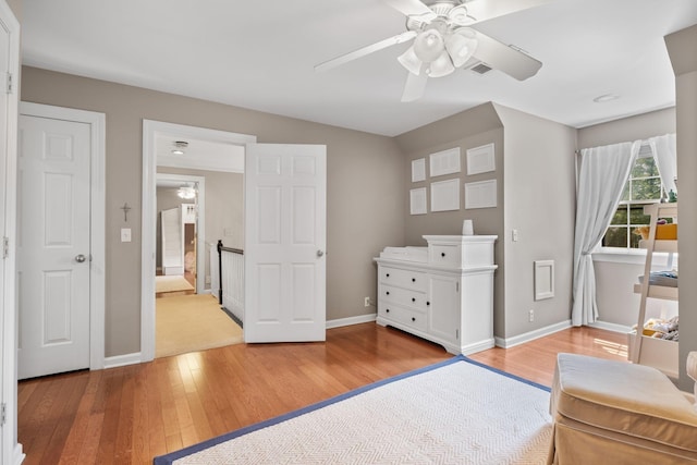 living area with light wood-style floors, a ceiling fan, visible vents, and baseboards