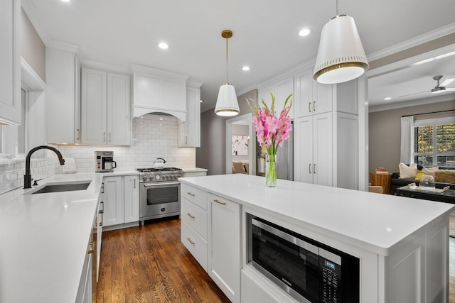 kitchen with a sink, tasteful backsplash, white cabinets, appliances with stainless steel finishes, and dark wood finished floors