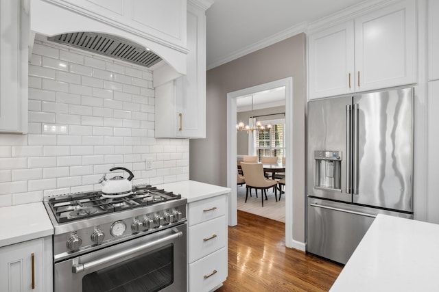 kitchen featuring a chandelier, high end appliances, backsplash, light countertops, and white cabinets
