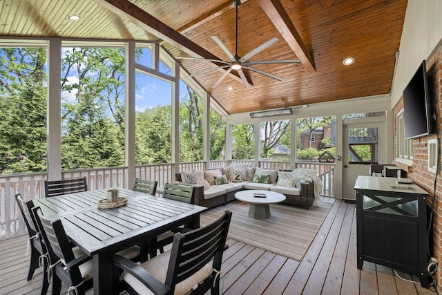 sunroom featuring a healthy amount of sunlight, beamed ceiling, ceiling fan, and an outdoor hangout area