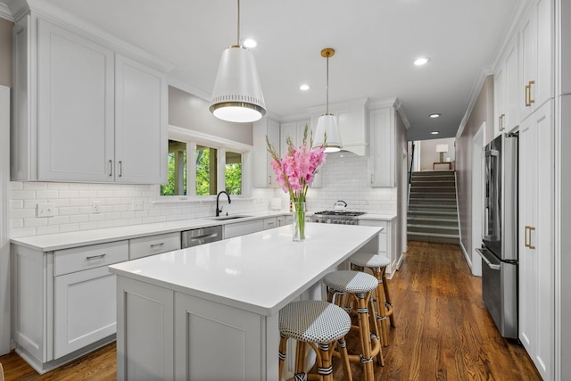 kitchen featuring a breakfast bar area, tasteful backsplash, a sink, appliances with stainless steel finishes, and light countertops