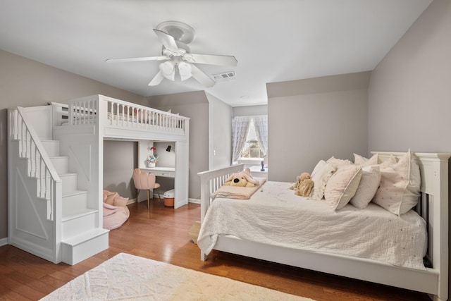 bedroom with wood finished floors, visible vents, ceiling fan, and baseboards