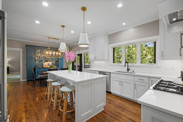 kitchen with decorative backsplash, ornamental molding, dishwasher, a sink, and a center island