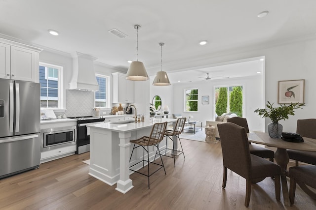 kitchen with a sink, a kitchen breakfast bar, crown molding, white cabinets, and appliances with stainless steel finishes