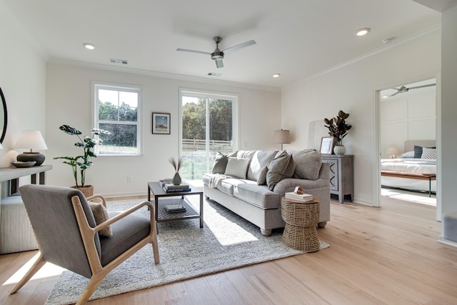 living area with visible vents, baseboards, ornamental molding, light wood finished floors, and a ceiling fan