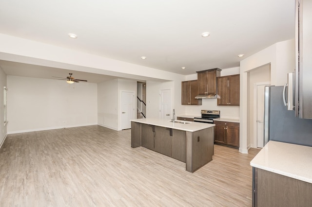 kitchen featuring a sink, light wood-style floors, light countertops, stainless steel appliances, and under cabinet range hood