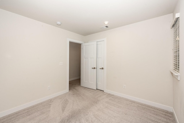 unfurnished bedroom featuring baseboards, carpet, and visible vents