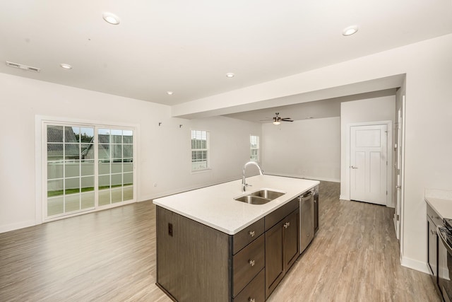 kitchen with stainless steel dishwasher, open floor plan, a sink, and light wood finished floors