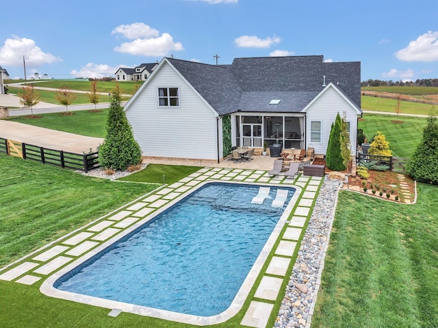 pool featuring a lawn, fence, a patio area, and a sunroom