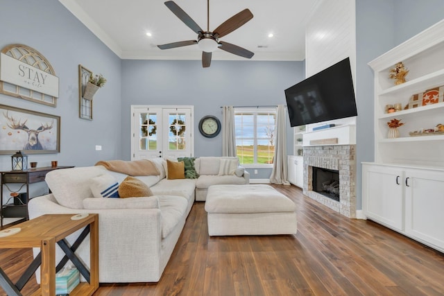 living room with dark wood-style floors, ceiling fan, crown molding, and a brick fireplace