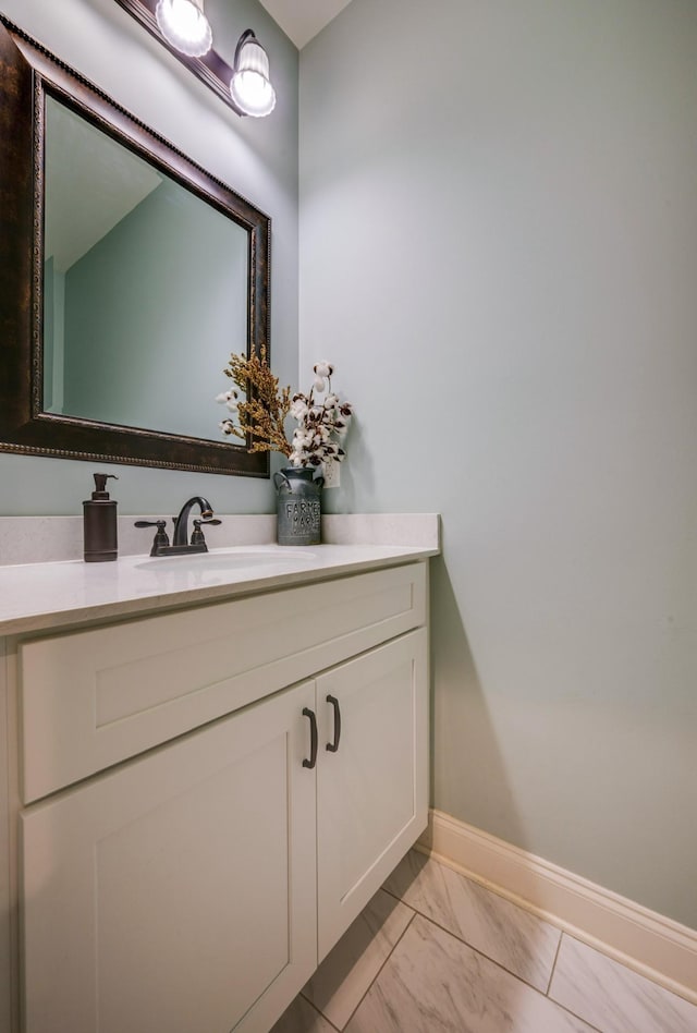 bathroom with marble finish floor, vanity, and baseboards