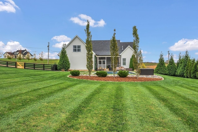 rear view of property with fence, an outdoor pool, a yard, and a sunroom
