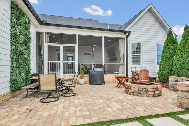 back of house featuring a patio area, roof with shingles, outdoor dining space, an outdoor fire pit, and a sunroom