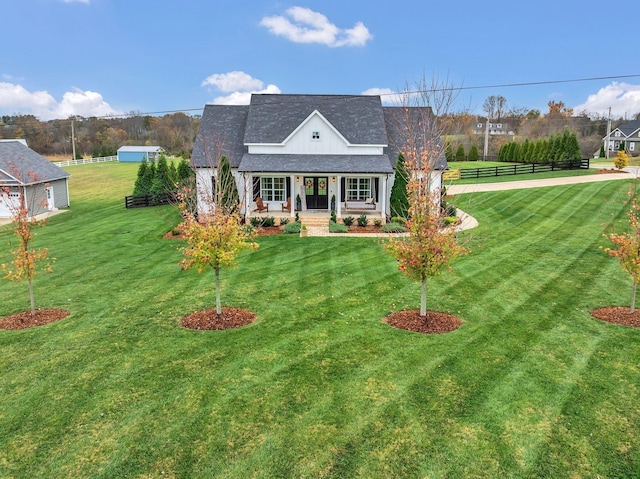 rear view of property featuring a lawn, a shingled roof, and covered porch