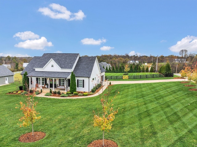 exterior space with covered porch, fence, a shingled roof, and a yard